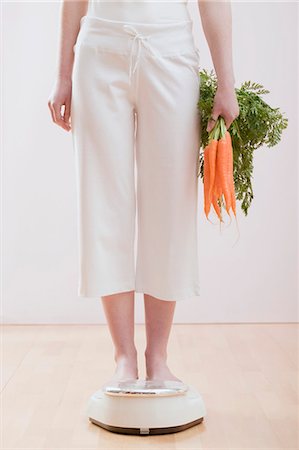 Young woman with carrots on bathroom scales Stock Photo - Premium Royalty-Free, Code: 659-03523372