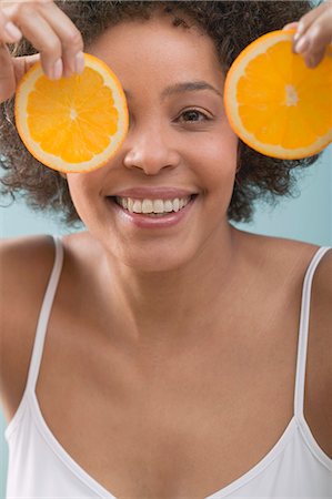 simsearch:659-03521659,k - Young woman holding orange slices in front of her face Foto de stock - Sin royalties Premium, Código: 659-03523384