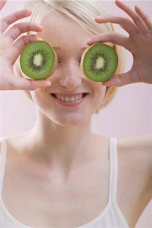 simsearch:659-01855145,k - Young woman with two kiwi fruit halves in front of her face Foto de stock - Royalty Free Premium, Número: 659-03523389