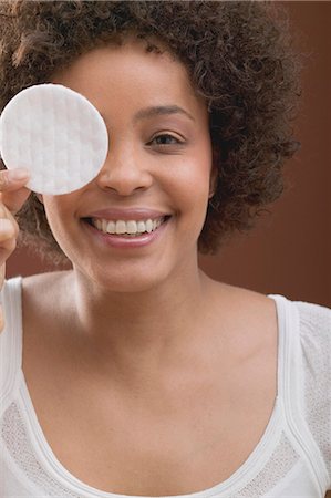 Young woman holding a cosmetic pad in front of her face Stock Photo - Premium Royalty-Free, Code: 659-03523382