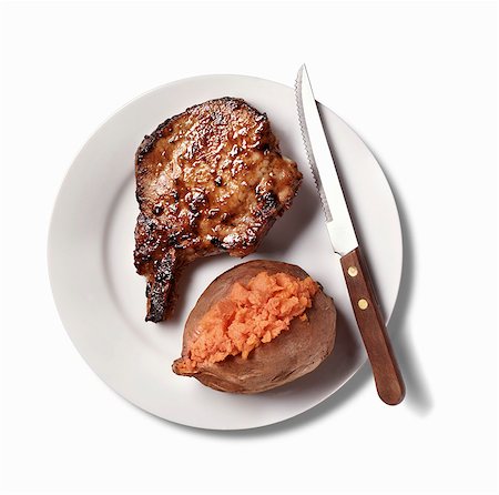 Pork Chop and Baked Sweet Potato on White Plate; White Background Stock Photo - Premium Royalty-Free, Code: 659-03535071