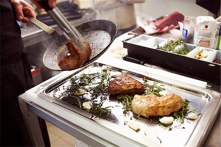 sauteeing - Placing the fried meat on a tray with herbs Stock Photo - Premium Royalty-Free, Code: 659-03535239