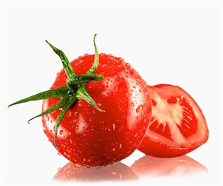 simsearch:659-06185964,k - Un entier et une tomate coupée en deux avec des gouttes d'eau Photographie de stock - Premium Libres de Droits, Code: 659-03535379