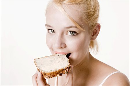 eaten - Young woman biting into a slice of bread and butter Stock Photo - Premium Royalty-Free, Code: 659-03535491