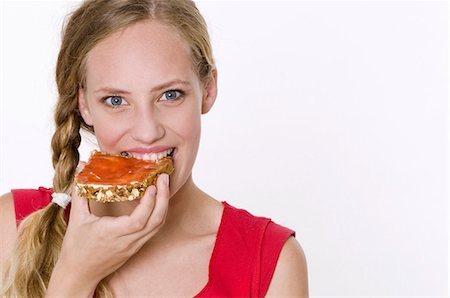 Young woman eating a slice of bread with strawberry and rhubarb jam Stock Photo - Premium Royalty-Free, Code: 659-03535505