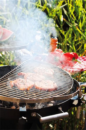 steak summer - Pork steaks on smoking barbecue out of doors Stock Photo - Premium Royalty-Free, Code: 659-03535962