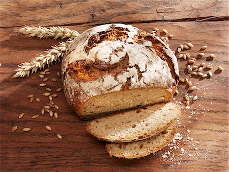 Rustic loaf of bread, partly sliced, ears & grains of wheat Foto de stock - Sin royalties Premium, Código: 659-03536325