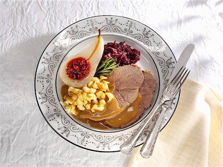 Leg of venison with spaetzle noodles, pear & red cabbage (overhead) Stock Photo - Premium Royalty-Free, Code: 659-03536336