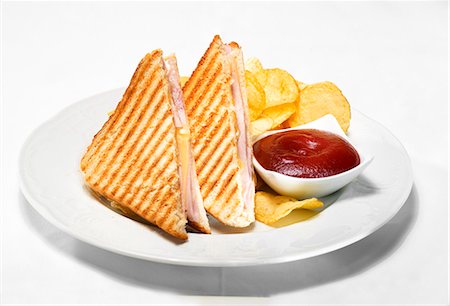 patatas fritas - Toasted ham and cheese sandwiches with ketchup and crisps Foto de stock - Sin royalties Premium, Código: 659-03536351