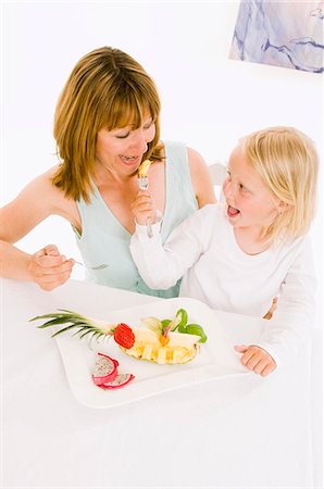 Mother and daughter eating fruit from plate Stock Photo - Premium Royalty-Free, Code: 659-03536928