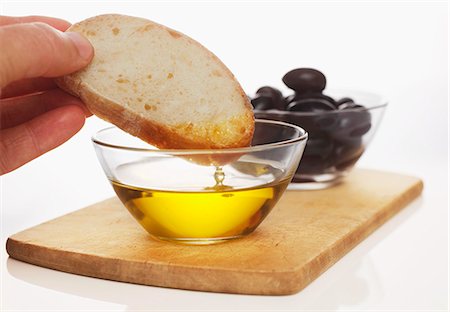 simsearch:659-06154910,k - Hand dipping slice of white bread in olive oil Fotografie stock - Premium Royalty-Free, Codice: 659-03537153