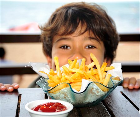 Garçon à table avec frites et ketchup Photographie de stock - Premium Libres de Droits, Code: 659-03537739