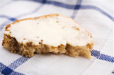 spreading butter on bread - Half a slice of bread and butter on tea towel Stock Photo - Premium Royalty-Free, Code: 659-03537896