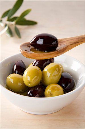 Green and black olives in small dish and on wooden spoon Stock Photo - Premium Royalty-Free, Code: 659-03537907