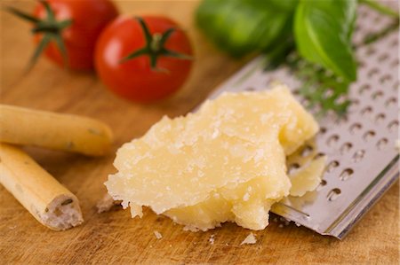 ralador de queijo - Parmesan with grater, grissini, tomatoes and basil Foto de stock - Royalty Free Premium, Número: 659-03537901