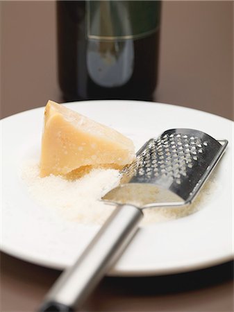 parmigiano - Parmesan, partly grated, with cheese grater on plate Fotografie stock - Premium Royalty-Free, Codice: 659-03530488