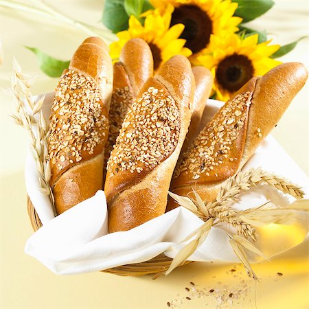 simsearch:659-03530672,k - Several Kornspitz rolls in bread basket, sunflowers, cereal ears Stock Photo - Premium Royalty-Free, Code: 659-03530673