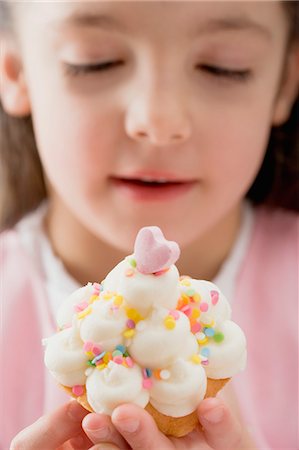 simsearch:659-03534803,k - Petite fille, tenant le petit gâteau avec la crème et le sucre de confettis Photographie de stock - Premium Libres de Droits, Code: 659-03530986