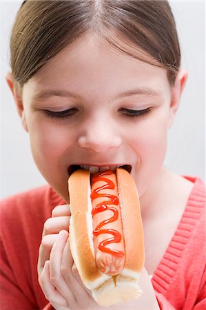 eaten - Girl biting into a hot dog Stock Photo - Premium Royalty-Free, Code: 659-03531007