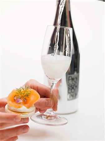 Hands holding cracker with smoked salmon & glass of Prosecco Stock Photo - Premium Royalty-Free, Code: 659-03531019