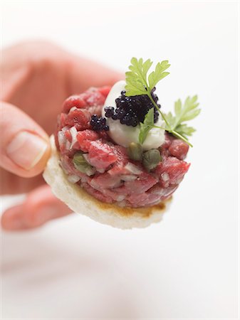 snack recipe - Hand reaching for tuna tartare canapé Stock Photo - Premium Royalty-Free, Code: 659-03531025