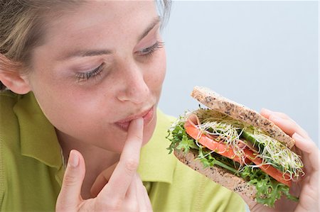 Jeune femme tenant sandwich et lécher son doigt Photographie de stock - Premium Libres de Droits, Code: 659-03531207