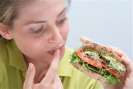 picture of american people eating - Young woman holding sandwich and licking her finger Stock Photo - Premium Royalty-Free, Code: 659-03531207