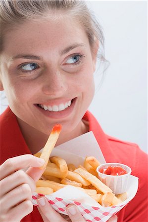 frite (aliment) - Femme souriante, manger un sac de croustilles Photographie de stock - Premium Libres de Droits, Code: 659-03531212