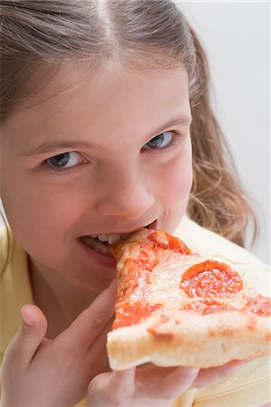 sausage eating - Girl biting into a slice of salami pizza Stock Photo - Premium Royalty-Free, Code: 659-03531227