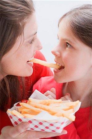 picture of american people eating - Young woman and girl eating the same chip Stock Photo - Premium Royalty-Free, Code: 659-03531222