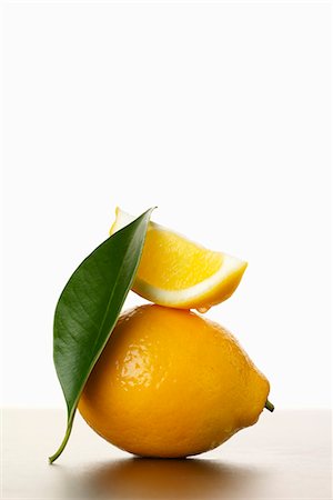 single lemon - Lemon Slice on Whole Lemon with Leaf Foto de stock - Sin royalties Premium, Código: 659-03531770