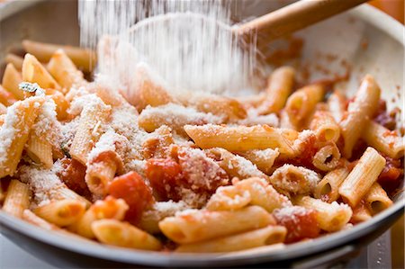 sprinkling - Adding Parmesan Cheese to Penne Pasta with Tomato Sauce in Saute Pan Stock Photo - Premium Royalty-Free, Code: 659-03532050