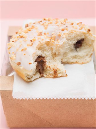 Iced doughnut with chocolate filling & chopped nuts, a bite taken Stock Photo - Premium Royalty-Free, Code: 659-03532240