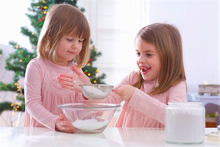 Christmas baking: two girls sieving icing sugar Stock Photo - Premium Royalty-Free, Code: 659-03533739