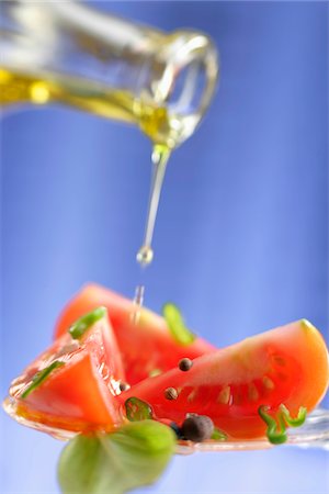 Pouring olive oil onto sliced tomatoes Stock Photo - Premium Royalty-Free, Code: 652-05808298