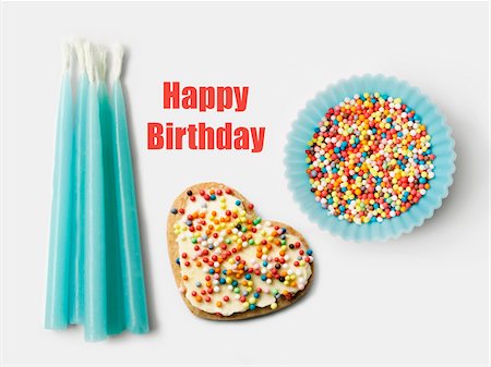 simsearch:652-05808845,k - Bougies d'anniversaire bleu, biscuits décorés et une tasse de papier bleu remplie de billes de sucre Photographie de stock - Premium Libres de Droits, Code: 652-05808855