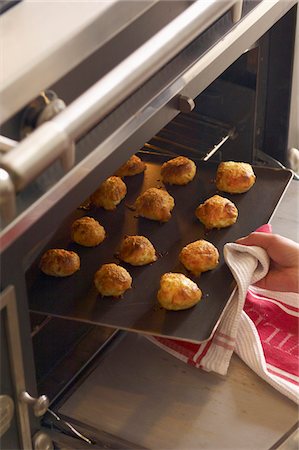 Taking the cheese choux pastries out of the oven Stock Photo - Premium Royalty-Free, Code: 652-05809397