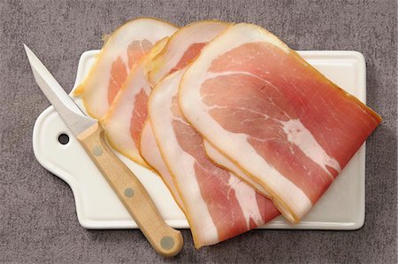 Slices of raw ham on a chopping board Stock Photo - Premium Royalty-Free, Code: 652-07656005