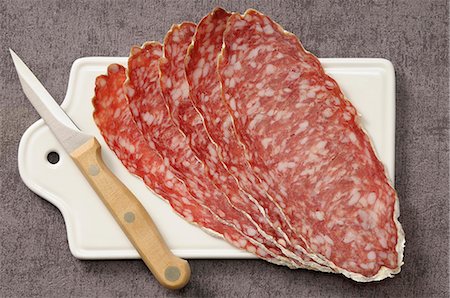 simsearch:652-07655937,k - Slices of large dried sausage on a chopping board Stock Photo - Premium Royalty-Free, Code: 652-07656021