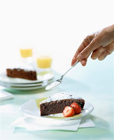 sprinkling chocolate cake with icing sugar Stock Photo - Premium Royalty-Free, Code: 652-01668603