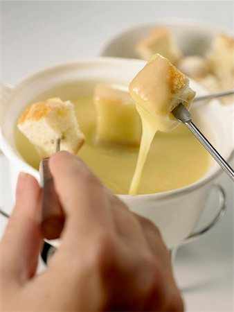 cheese fondue with cubes of bread and hand Stock Photo - Premium Royalty-Free, Code: 652-01668916