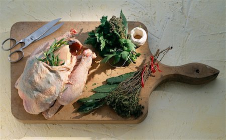 raw chicken on cutting board - Putting the herbs under the chicken's skin Stock Photo - Premium Royalty-Free, Code: 652-02221759