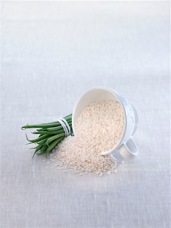 string bean - Spilt cup of rice and a bundle of green beans Stock Photo - Premium Royalty-Free, Code: 652-03635874