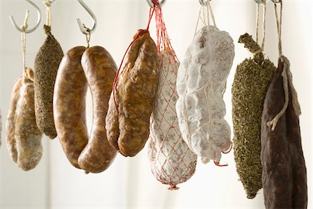 prato de frios - Variety of dried sausages hanging Foto de stock - Royalty Free Premium, Número: 652-03804426