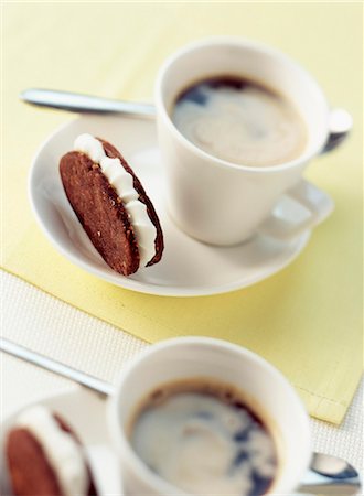 simsearch:652-03800478,k - Chocolate and hazelnut shortbread biscuits filled with sugar ganache and cups of coffee Foto de stock - Sin royalties Premium, Código: 652-03800478