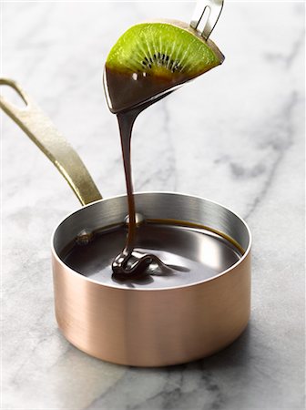 Dipping a slice of kiwi into a saucepan of melted chocolate Stock Photo - Premium Royalty-Free, Code: 652-03802247