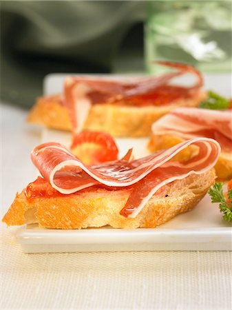 Spanish ham and tomato on a bite-size slice of bread Stock Photo - Premium Royalty-Free, Code: 652-03802573