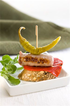 simsearch:652-03802569,k - Red pepper,sausage and Guindilla pepper on a bite-size slice of bread Foto de stock - Sin royalties Premium, Código: 652-03802586