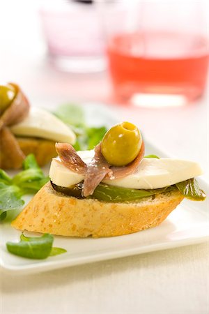 Anchovy,cheese,green pepper and olive on a bite-size slice of bread Stock Photo - Premium Royalty-Free, Code: 652-03802609