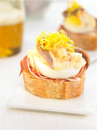 simsearch:652-03802633,k - Jambon Serrano, anchois, crevettes et oeufs sur une tranche de bouchées de pain Photographie de stock - Premium Libres de Droits, Code: 652-03802610